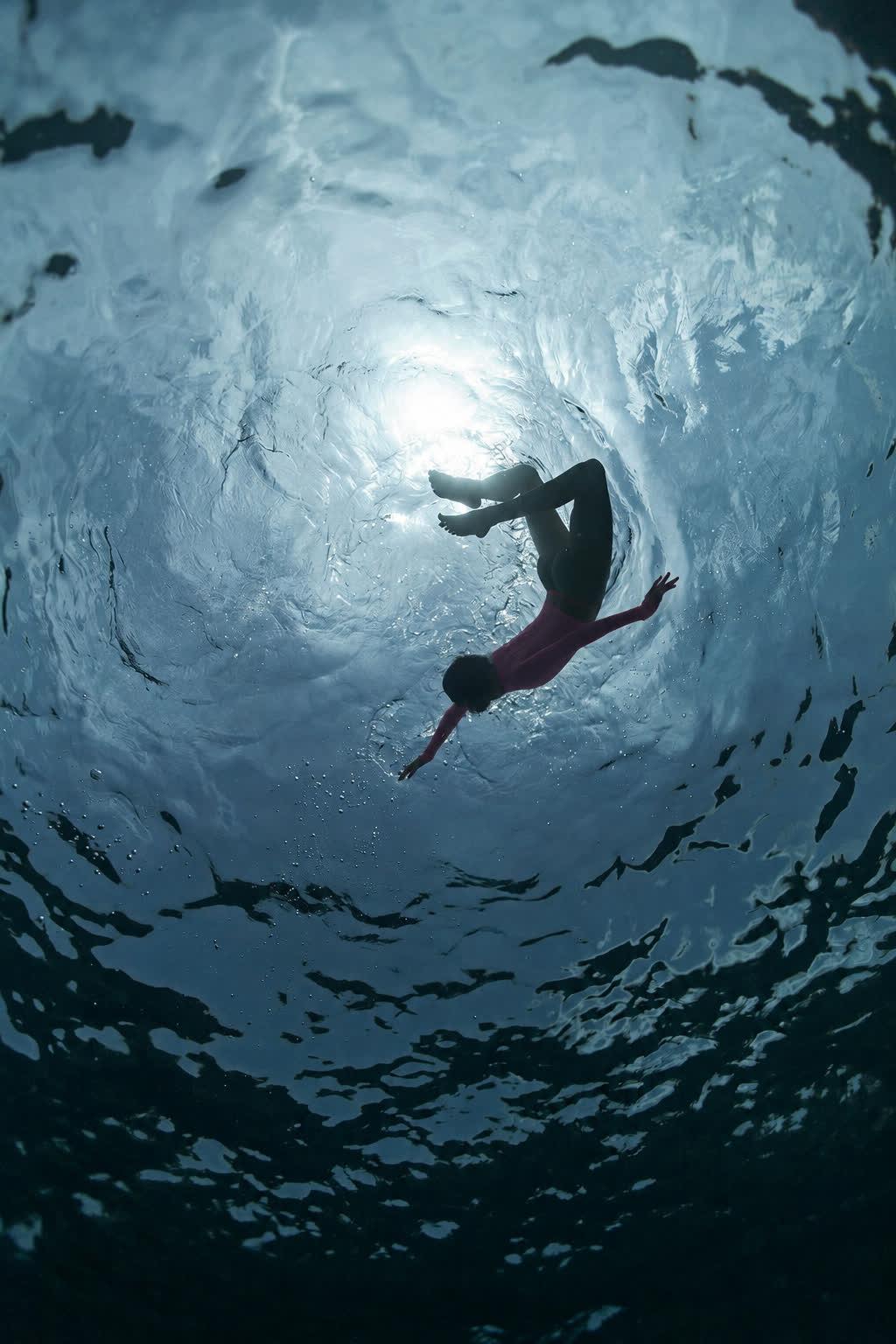 Diving under the surface in the pink rashvest, shot from below